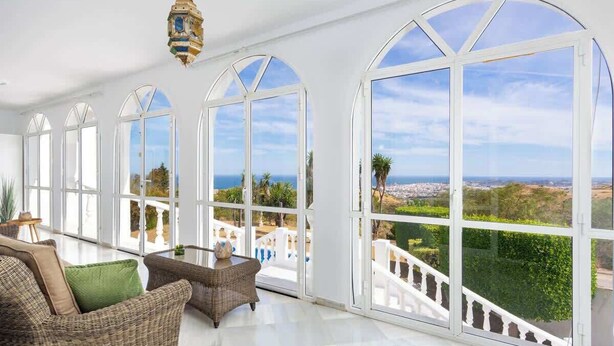 A spacious room with large arched windows offering a view of the sea and a white staircase leading to a balcony. - Villa Sabah with sea views near Mijas Pueblo - REF 119 (Mijas)