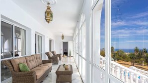 A spacious balcony with wicker furniture, large windows, and a view of the sea. - Villa Sabah with sea views near Mijas Pueblo - REF 119 (Mijas)