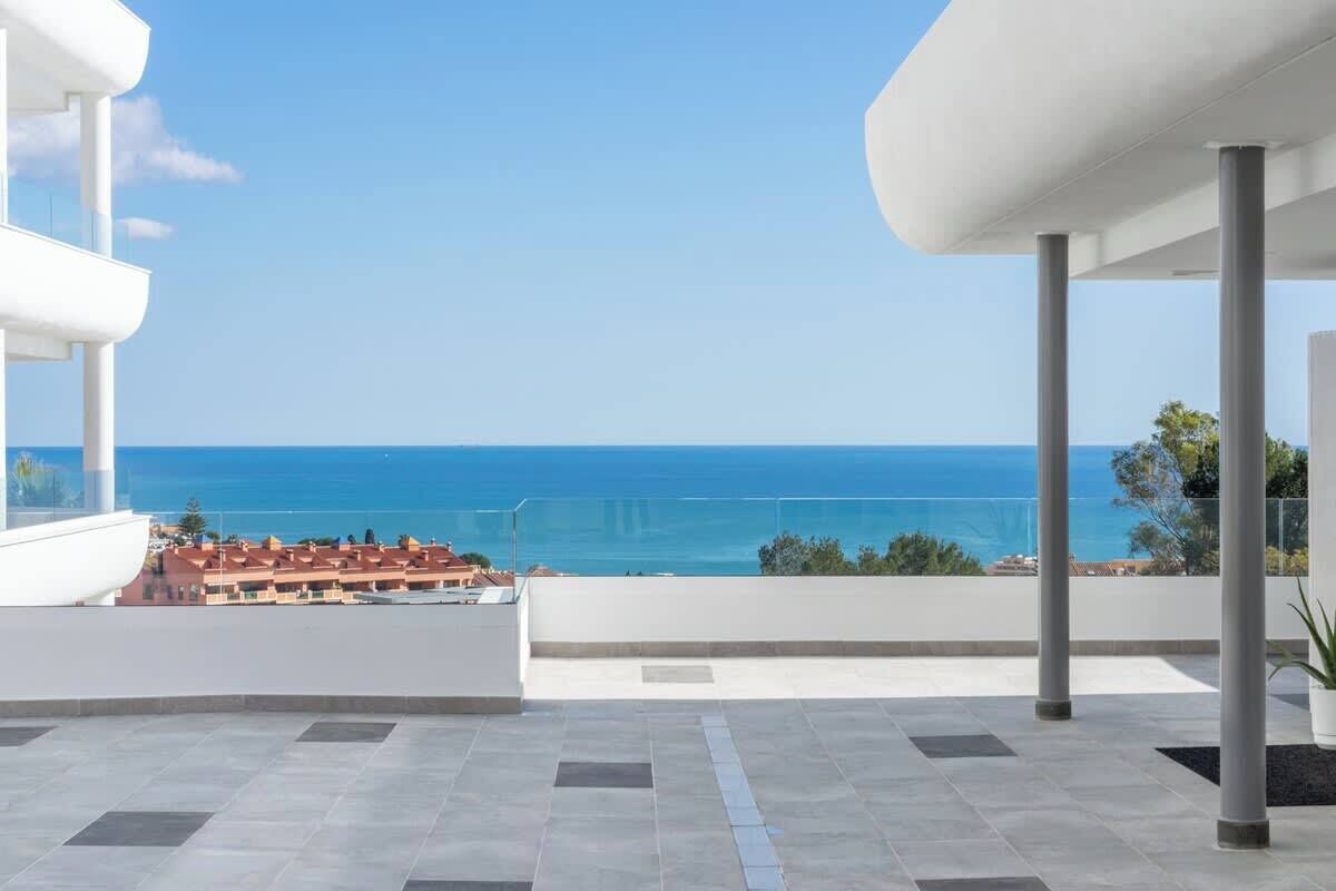 Een balkon met uitzicht op zee en een stad in de verte.