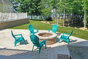 Relax by the fire pit surrounded by comfortable Adirondack chairs in a serene outdoor setting.