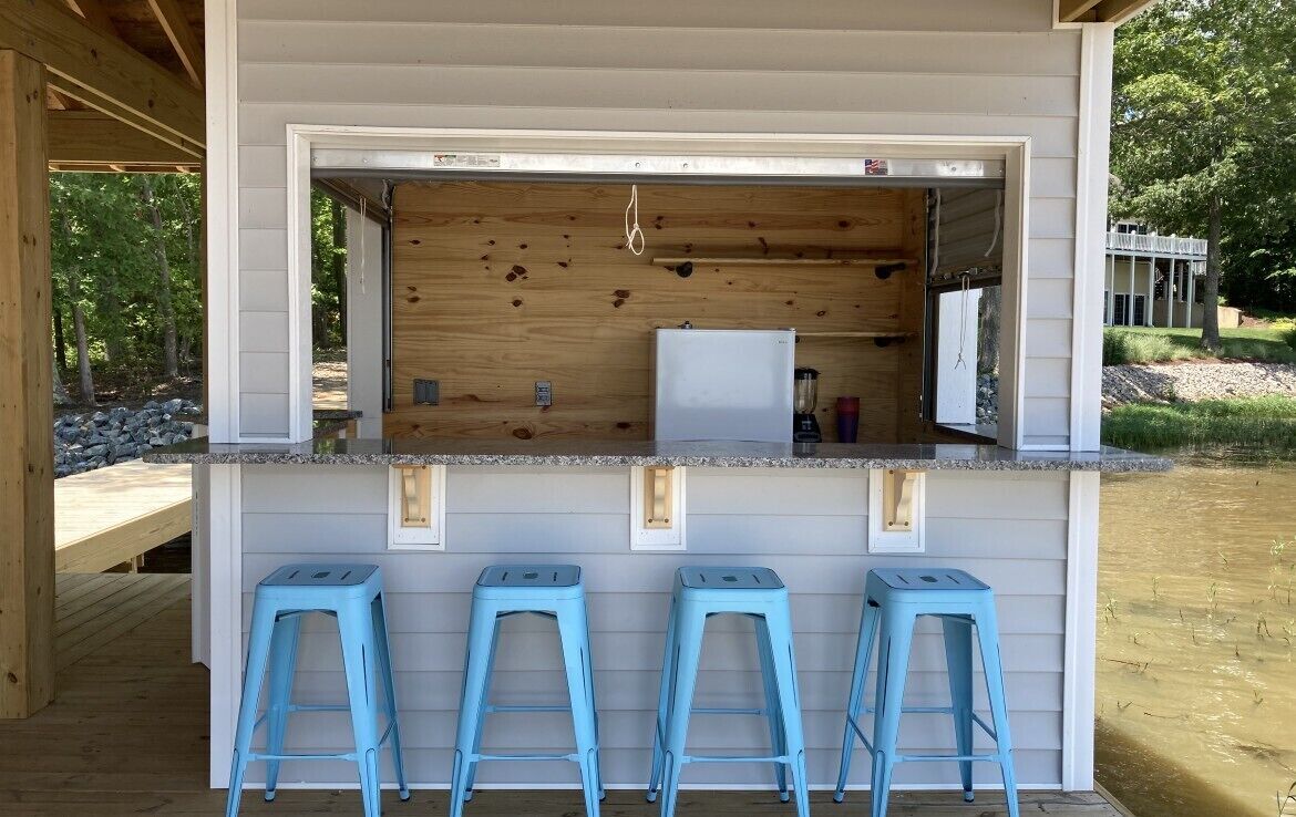 A wooden bar area with a white countertop and three blue stools.
