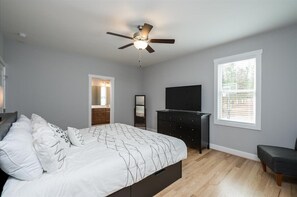 Relax in this serene bedroom with a comfortable bed, flat-screen TV, and ceiling fan.