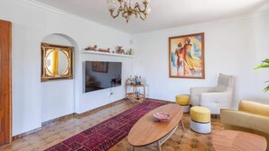 A spacious living room with a large TV, a chandelier, a painting, and a red carpet. - Stunning Villa with Pool by Costarentals - Ref 30 (Fuengirola)