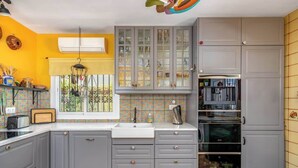 A kitchen with grey cabinets, a white sink, and a window with a view of greenery. - Stunning Villa with Pool by Costarentals - Ref 30 (Fuengirola)