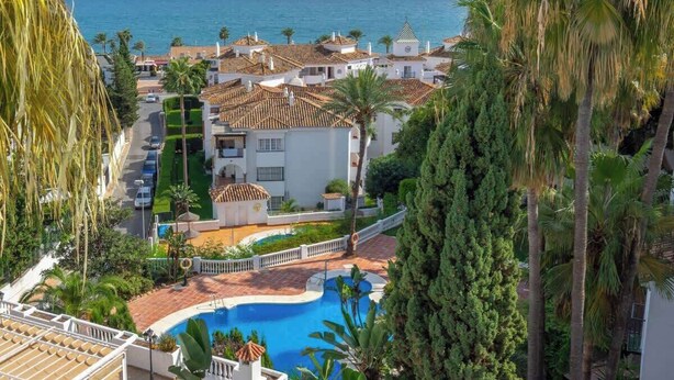A coastal property with a swimming pool, palm trees, and a view of the sea. - Benalmádena with sauna by Costarentals - Ref 72 (Benalmádena)
