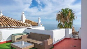 A rooftop terrace with a wicker sofa, a glass table, and a view of the sea. - Benalmádena with sauna by Costarentals - Ref 72 (Benalmádena)