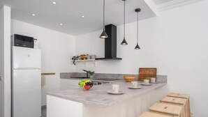 Una cocina moderna con isla integrada, muebles blancos y una campana extractora negra.