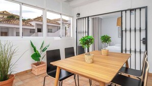 Comedor con una mesa de madera, sillas negras y plantas en macetas.