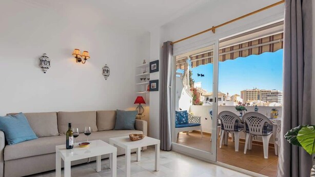 Un salon moderne comprenant un canapé, deux tables basses et un coin repas avec des chaises.