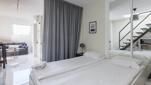 A modern hotel room with a large bed, a desk, a chair, a sofa, and a staircase. - Modern sea view rooftop by Costarentals - Ref 116 (Fuengirola)