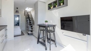 A modern kitchen with a built-in TV, a staircase, and a dining area with two chairs. - Modern sea view rooftop by Costarentals - Ref 116 (Fuengirola)