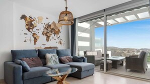 Un salon moderne avec un canapé bleu, une table basse en verre et une fresque murale représentant une carte du monde.