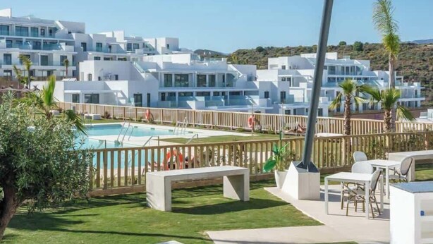 Un complexe hôtelier avec des bâtiments blancs, une piscine, des espaces de détente en plein air et une vue dégagée sur le paysage.