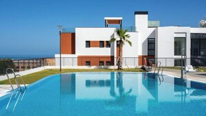 A modern hotel with a swimming pool, a view of the sea, and a well-maintained lawn. - Modern Apartment w/ Pool & Gym Near Beach Access (Málaga)