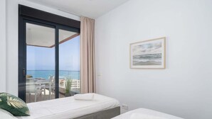 A hotel room with a balcony, a bed, a bedside table, and a framed picture on the wall. - Modern Apartment w/ Pool & Gym Near Beach Access (Málaga)