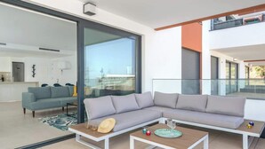 A modern living room with a grey sectional sofa, two coffee tables, and a glass door leading to a balcony. - Modern Apartment w/ Pool & Gym Near Beach Access (Málaga)