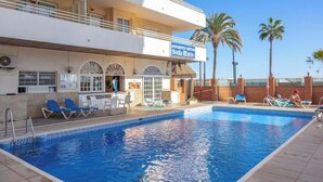 A hotel with a swimming pool, lounge chairs, and palm trees. - Beachfront Stella Maris by Costarentals - Ref 36 (Fuengirola)