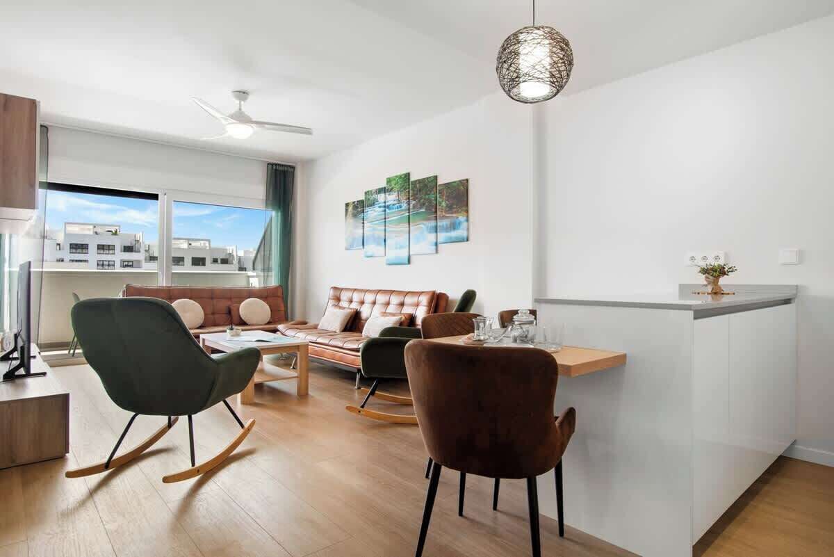 A modern living room with a sofa, a dining table, and a kitchen island.
