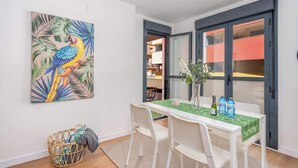 A dining area with a table set for two, a wicker basket, and a tropical bird painting on the wall. - Central couples getaway by Costarentals - Ref 155 (Fuengirola)
