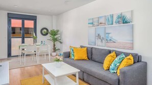 A modern living room with a grey sofa, yellow cushions, a white coffee table, and a dining area with white chairs and a table. - Central couples getaway by Costarentals - Ref 155 (Fuengirola)