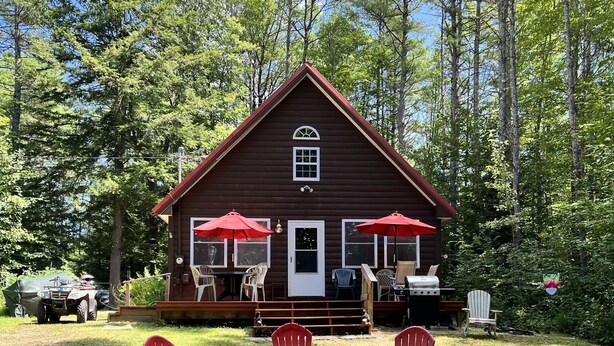 A cabin with a deck, outdoor seating, and a fire pit.