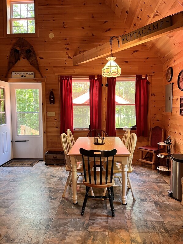 A wooden cabin interior with a dining table, chairs, a chandelier, and a sign reading 'Hancock Pond'. - Knotty pine log cabin - boating, fishing, ATV trails and hiking! (Denmark)