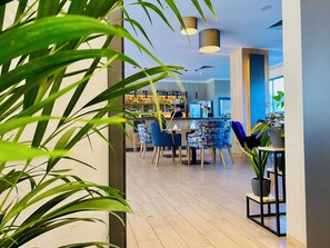 A modern interior with a bar area, wooden flooring, and patterned chairs. - CONRAD Comfort Hotel**** (Kraków)
