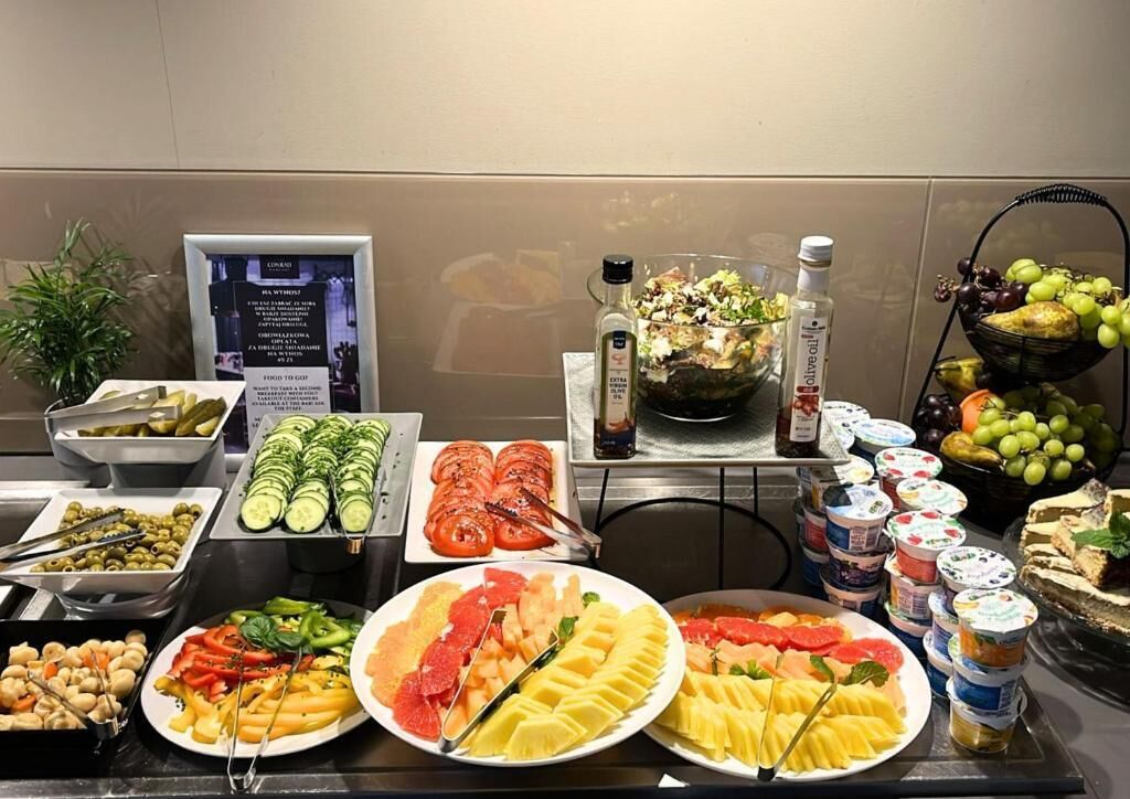 A buffet with various food items including sliced cucumbers, tomatoes, and a salad.