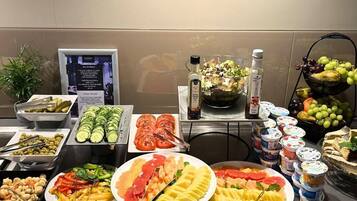 A buffet with various food items including sliced cucumbers, tomatoes, and a salad.