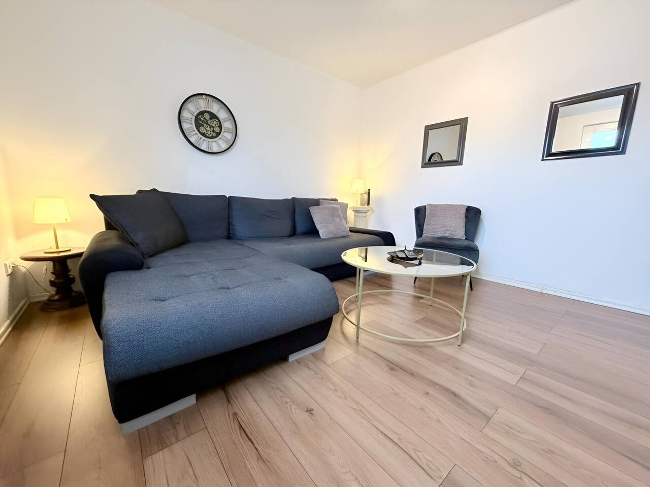 Een moderne woonkamer met een modulaire bank, een ronde salontafel en twee fauteuils.