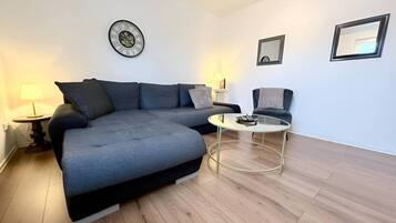 Een moderne woonkamer met een modulaire bank, een ronde salontafel en twee fauteuils.