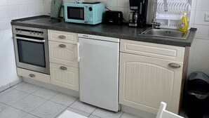 A compact kitchen with white cabinets, a microwave, a toaster, a coffee maker, and a dishwasher. - FeWo Lindenallee – Modern & Ruhig (Nordhorn)