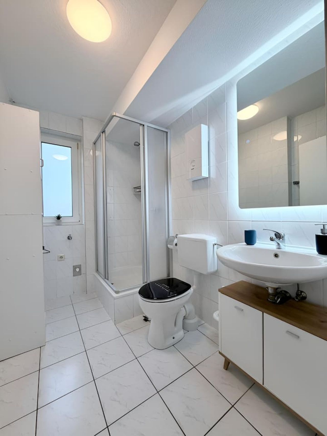 Ein modernes Badezimmer mit einer gläsernen Duschkabine, einer weißen Toilette und einem Waschbecken mit Spiegel darüber.