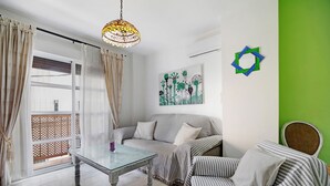 A room with a glass table, striped sofa, and a green accent wall. - Apartment 'Casa Milagros' close to the Sea with Balcony (Sanlúcar de Barrameda)