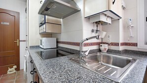 A kitchen with a granite countertop, stainless steel sink, and a microwave. - Apartment 'Casa Milagros' close to the Sea with Balcony (Sanlúcar de Barrameda)