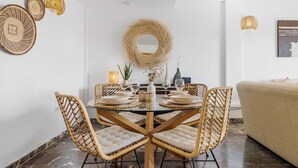 A dining area with a round table, four wicker chairs, and a beige sofa.