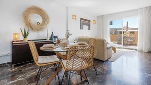 A modern dining area with a glass table, wicker chairs, and a view to an outdoor balcony.