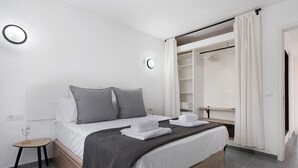 Un dormitorio moderno con cama, mesita de noche y vestidor.
