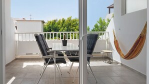 Un balcon avec une table et des chaises, un hamac et une vue sur la verdure.