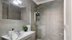 Une salle de bain moderne avec une douche, un lavabo et un miroir.