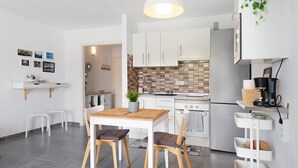 Una cocina moderna con armarios blancos, una mesa de comedor de madera y una planta colgante.