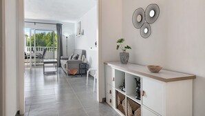 Un interior moderno con una consola blanca, una planta en maceta y un elemento decorativo en la pared.