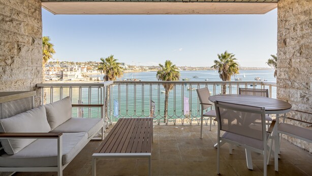 Un balcon avec vue sur la mer, un canapé, une table et des chaises.