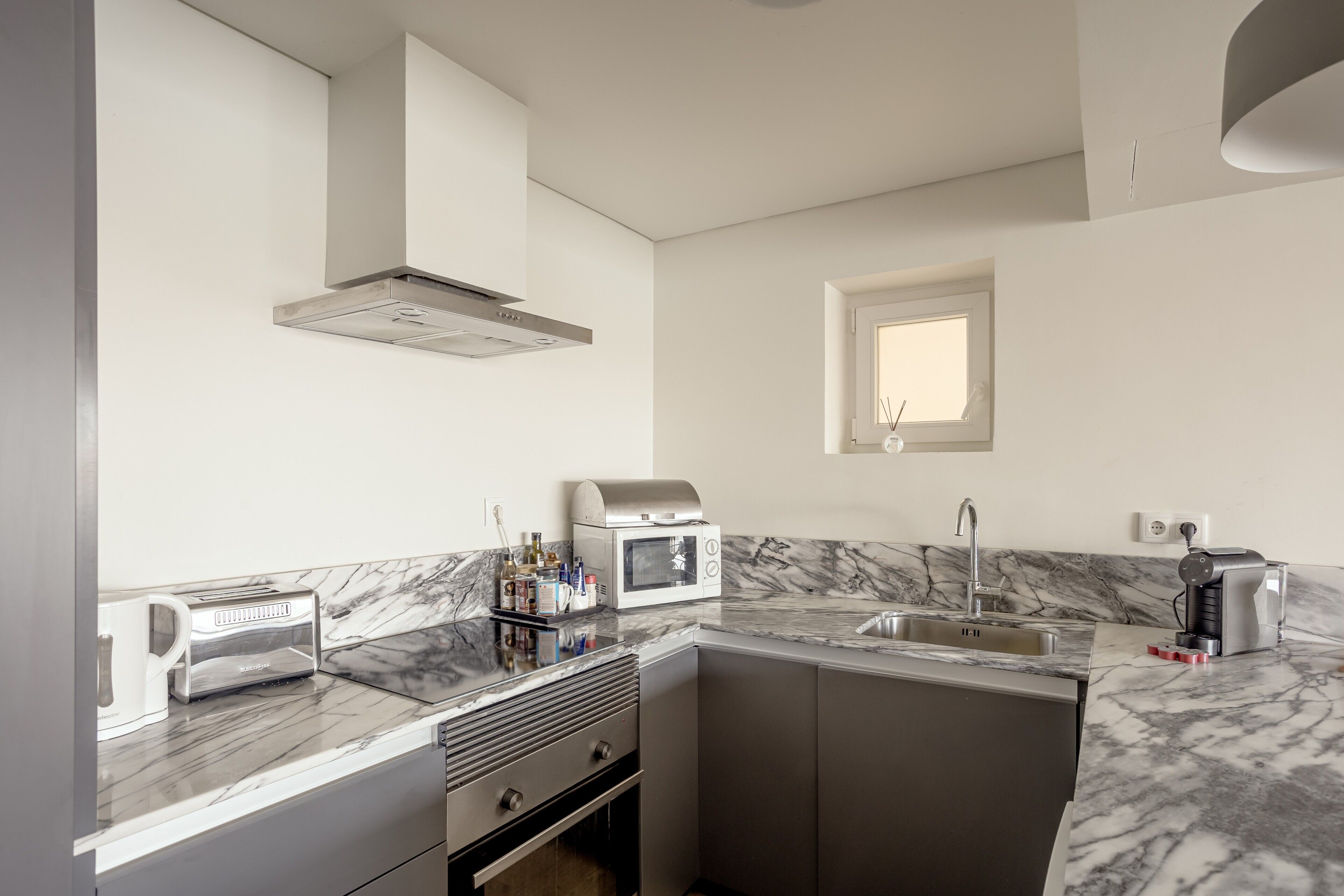 A compact kitchen with a microwave, toaster, and sink.