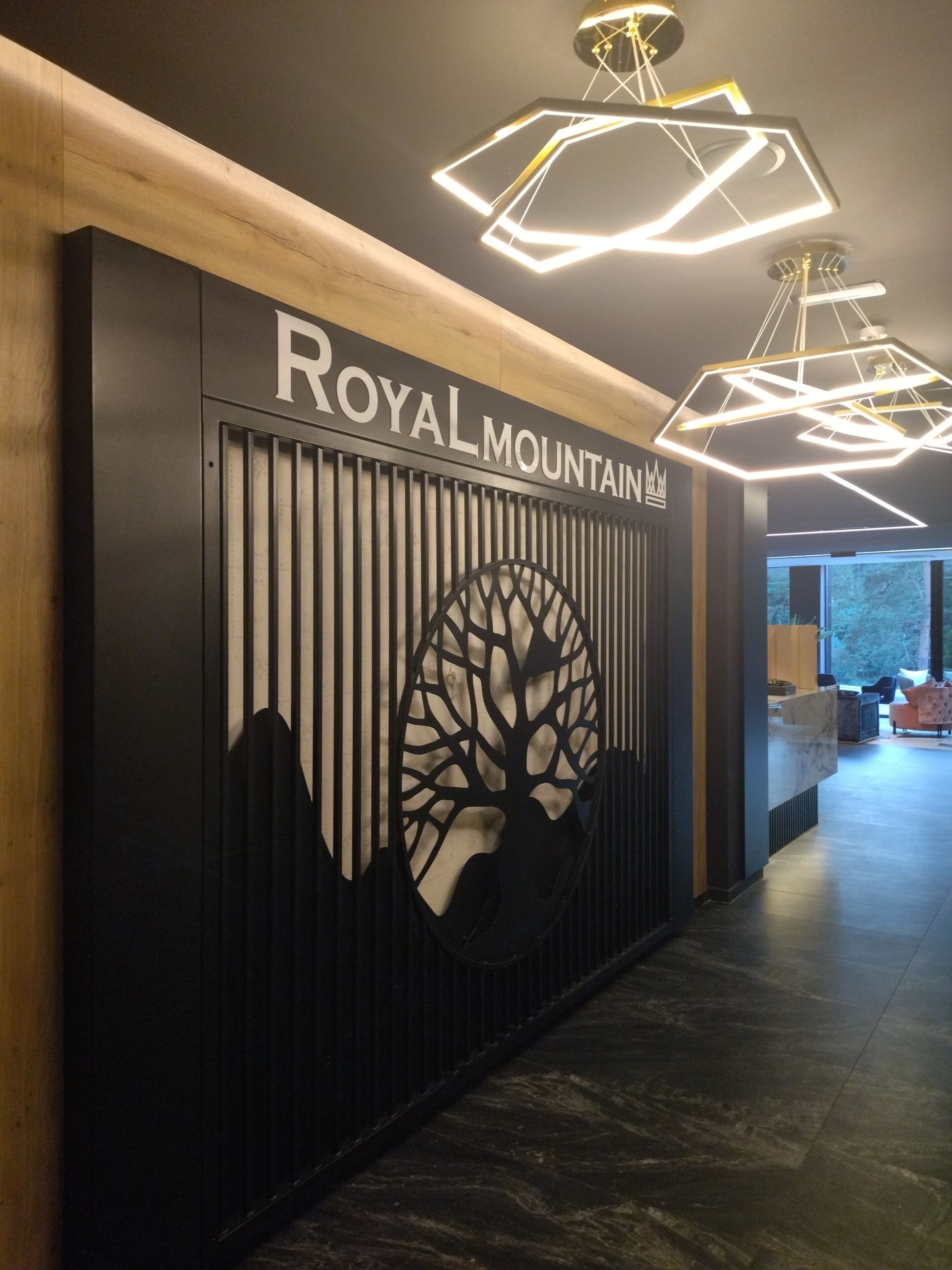 A reception area with a sign reading "ROYAL MOUNTAIN" and a modern geometric light fixture above.