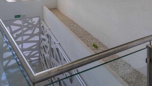 Un intérieur moderne avec un mur vert à texture, des rampes blanches et un plafond au motif géométrique.