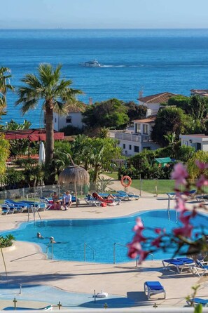 A pool area with lounge chairs, palm trees, and a view of the ocean. - Spacious El Faro Penthouse w/ Pool & Beach Access (Málaga)