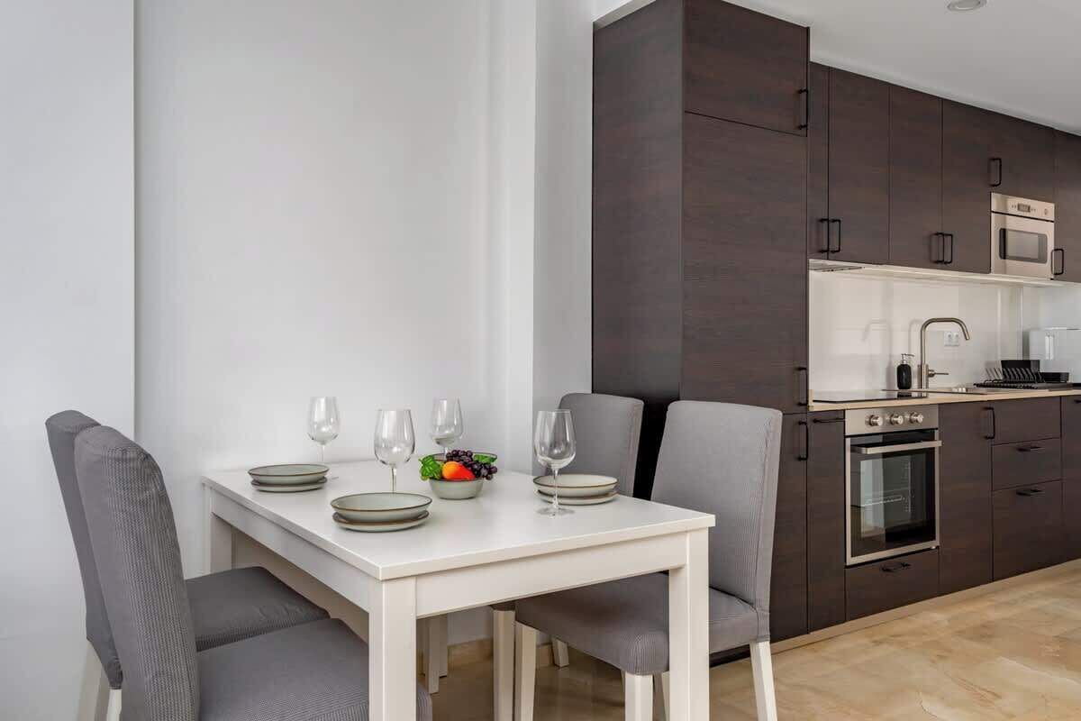 Una cocina moderna con armarios oscuros, encimera blanca y horno empotrado.