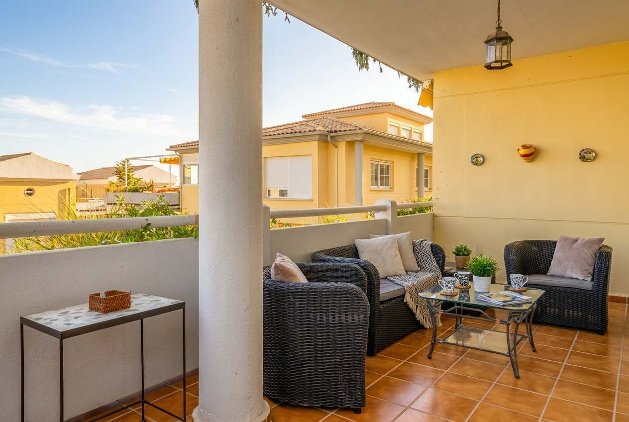 A balcony with wicker furniture, a small table, and a hanging light fixture.