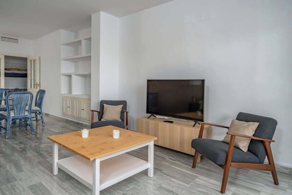 Una sala de estar con una mesa de centro de madera, dos sillones, un televisor y un aparador.